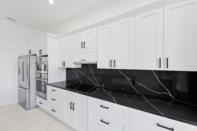 kitchen with dark stone counters, white cabinetry, tasteful backsplash, and stainless steel appliances