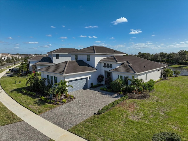 traditional-style home featuring a garage, a tiled roof, decorative driveway, and a front yard