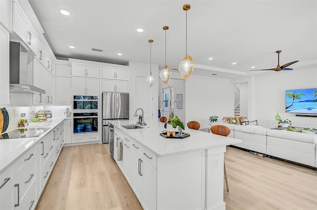 kitchen featuring a breakfast bar, sink, decorative light fixtures, a center island with sink, and white cabinets