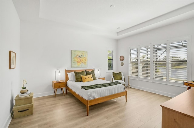 bedroom featuring a tray ceiling and light hardwood / wood-style flooring