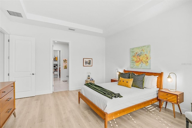 bedroom featuring a raised ceiling and light wood-type flooring