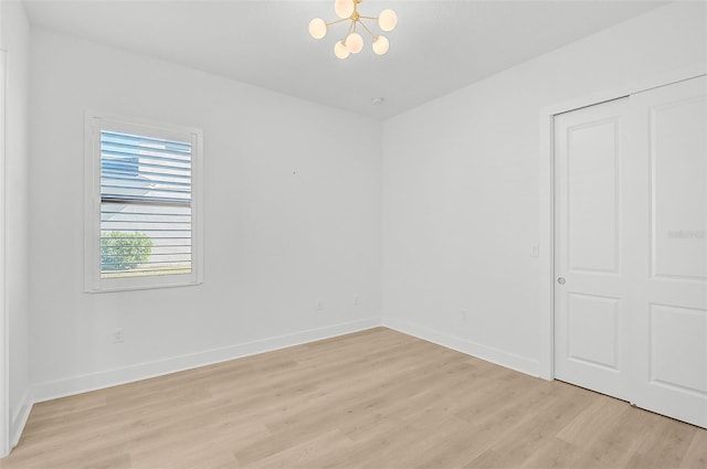 spare room featuring light hardwood / wood-style flooring and a chandelier