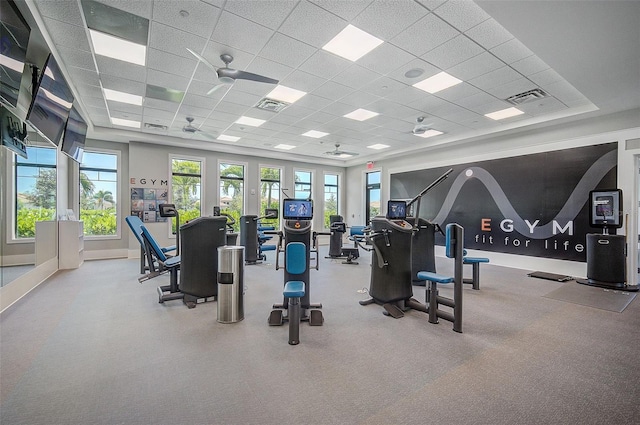 workout area with a paneled ceiling, ceiling fan, and a healthy amount of sunlight