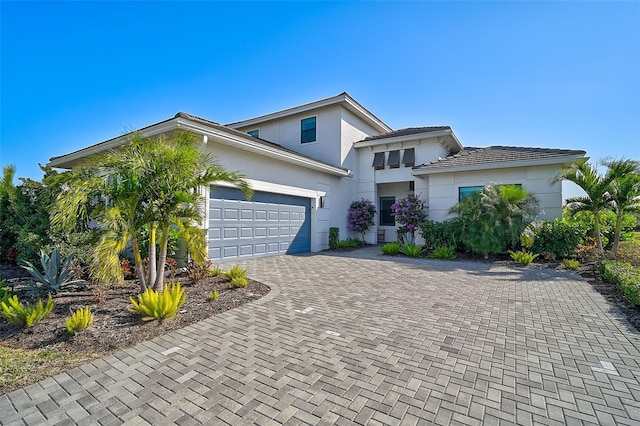 view of front facade featuring a garage, decorative driveway, and stucco siding