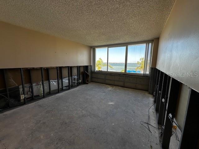 spare room with a water view, concrete flooring, and a textured ceiling