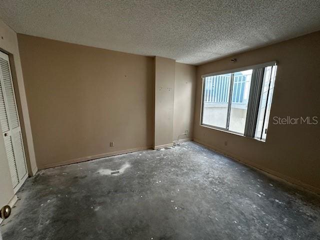 unfurnished room with a textured ceiling and concrete floors