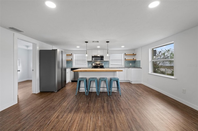 kitchen featuring a center island, stainless steel appliances, wood counters, dark hardwood / wood-style floors, and white cabinets