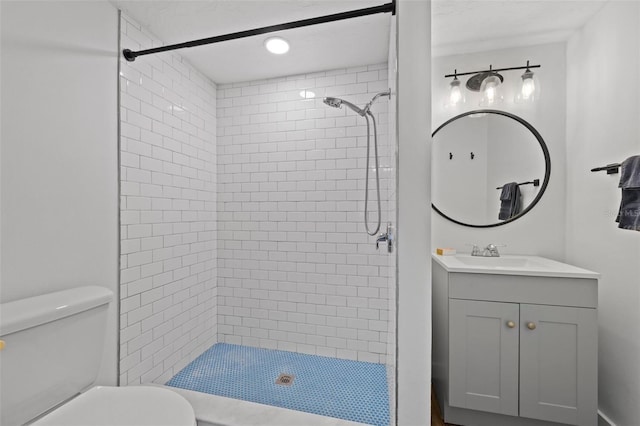 bathroom with a tile shower, vanity, and toilet