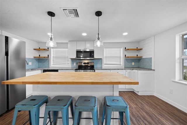 kitchen featuring butcher block counters, white cabinetry, a center island, and appliances with stainless steel finishes