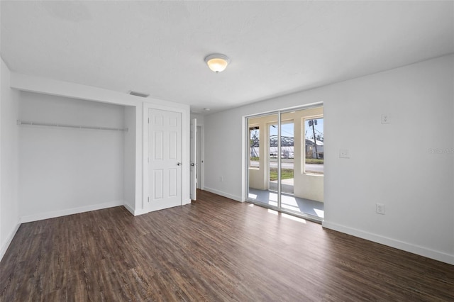 unfurnished bedroom featuring access to exterior, dark hardwood / wood-style floors, and a closet