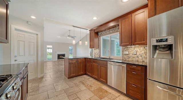 kitchen with sink, kitchen peninsula, pendant lighting, decorative backsplash, and appliances with stainless steel finishes