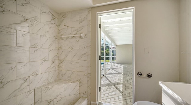 bathroom with a tile shower and lofted ceiling