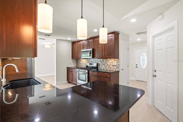 482 Rubens Dr E, Nokomis, FL 34275 - kitchen featuring stainless steel appliances, backsplash, dark stone countertops, recessed lighting, and pendant lighting