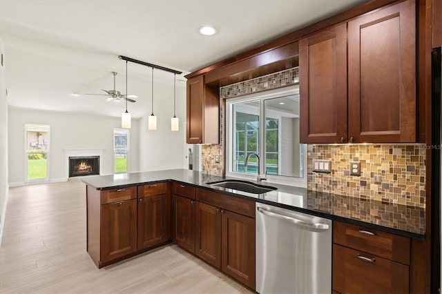 482 Rubens Dr E, Nokomis, FL 34275 - kitchen featuring stainless steel dishwasher, backsplash, a ceiling fan, a peninsula, and a warm lit fireplace