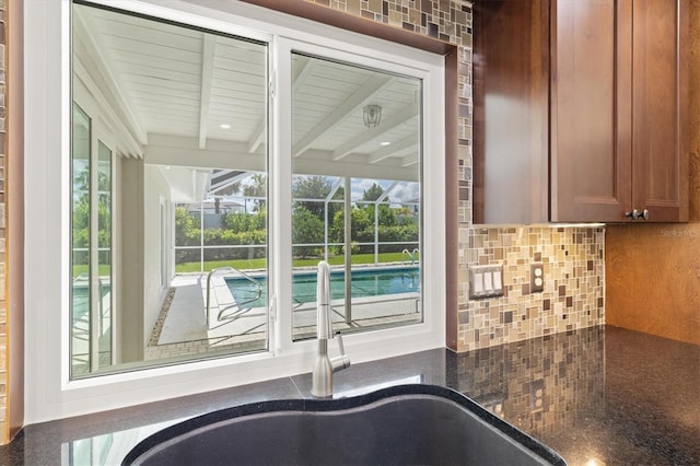 482 Rubens Dr E, Nokomis, FL 34275 - kitchen view of tasteful backsplash, brown cabinetry, and dark stone countertops