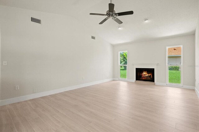 482 Rubens Dr E, Nokomis, FL 34275 - unfurnished living room featuring healthy amount of natural light, a lit fireplace, a ceiling fan, light wood-style flooring, and high vaulted ceiling