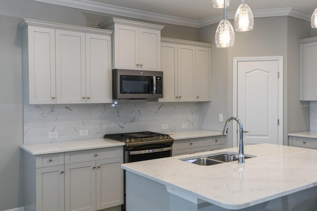 kitchen featuring pendant lighting, a kitchen island with sink, sink, decorative backsplash, and appliances with stainless steel finishes