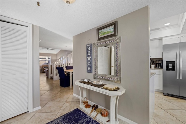 corridor with a textured ceiling and light tile patterned floors