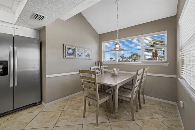 dining space with lofted ceiling, a textured ceiling, and light tile patterned floors