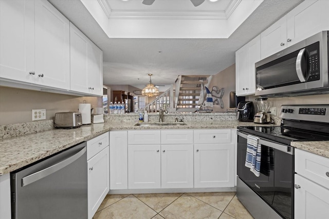 kitchen with stainless steel appliances, white cabinetry, a tray ceiling, and sink