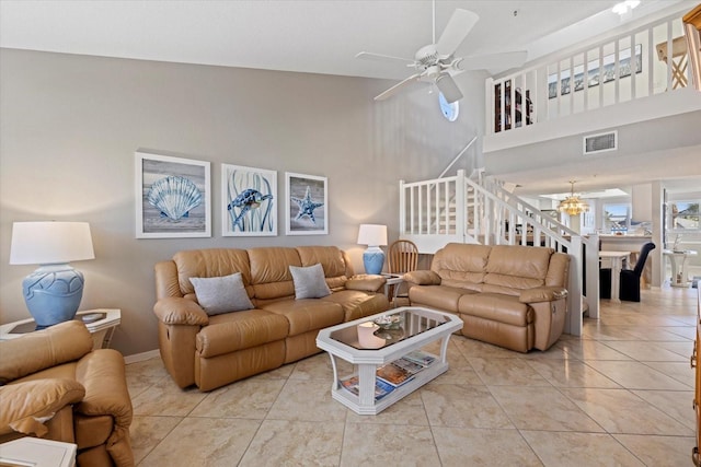 tiled living room with ceiling fan with notable chandelier and a towering ceiling