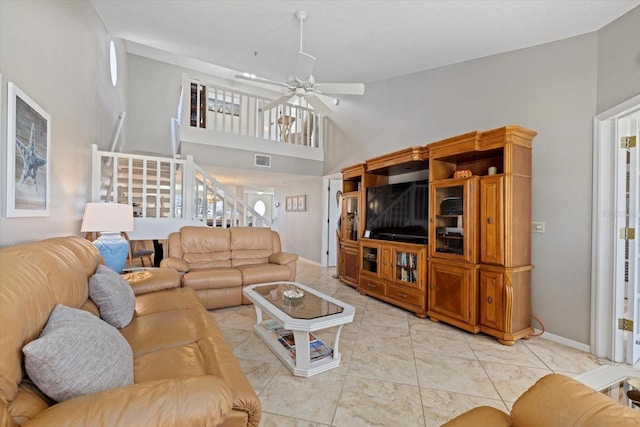 tiled living room featuring ceiling fan and a high ceiling