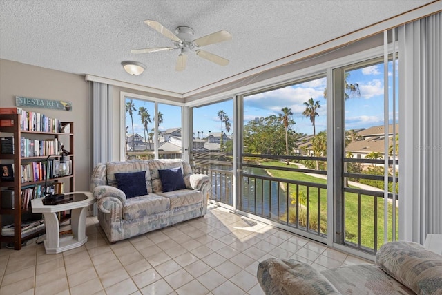 sunroom / solarium with ceiling fan and a water view