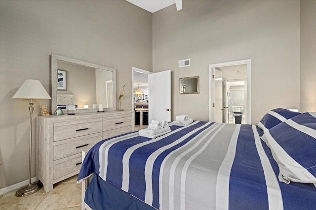 tiled bedroom featuring a towering ceiling and ensuite bathroom