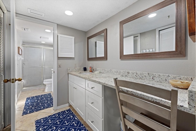 bathroom with toilet, a textured ceiling, a shower with door, tile patterned floors, and vanity