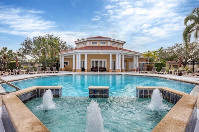 view of pool featuring pool water feature, french doors, and a hot tub