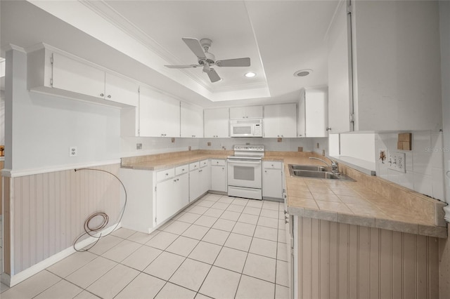 kitchen featuring sink, white cabinetry, white appliances, light tile patterned floors, and a tray ceiling