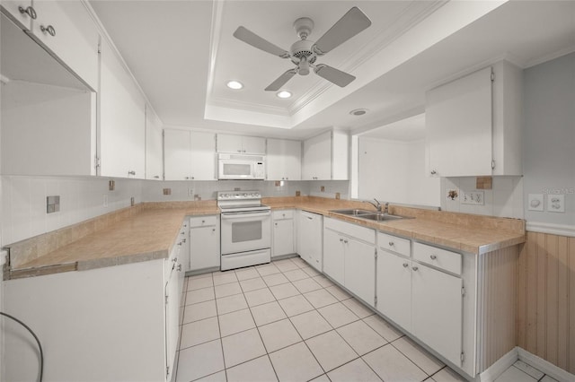 kitchen featuring white appliances, sink, a tray ceiling, and white cabinetry