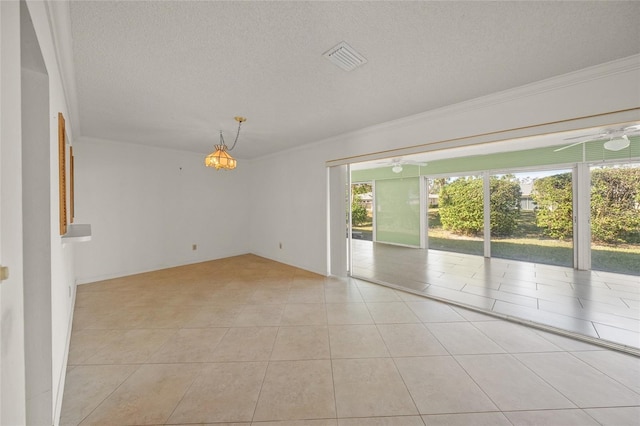 tiled empty room featuring a textured ceiling and crown molding