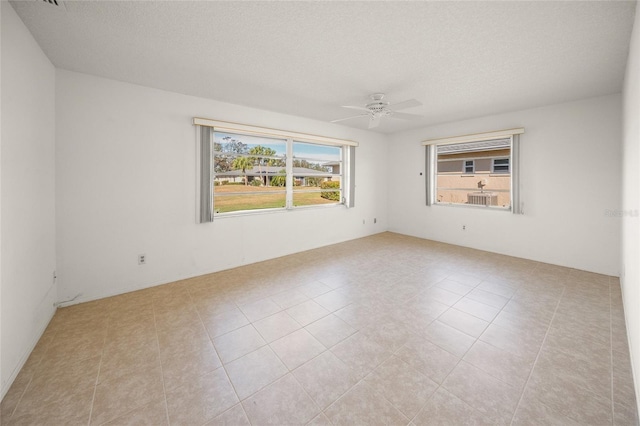 tiled spare room with a textured ceiling and ceiling fan