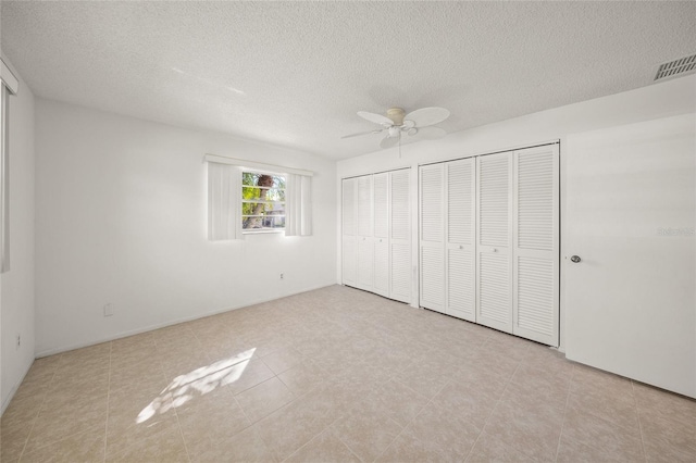 unfurnished bedroom featuring a textured ceiling, two closets, ceiling fan, and light tile patterned floors