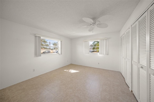 unfurnished bedroom featuring a textured ceiling, ceiling fan, a closet, and multiple windows