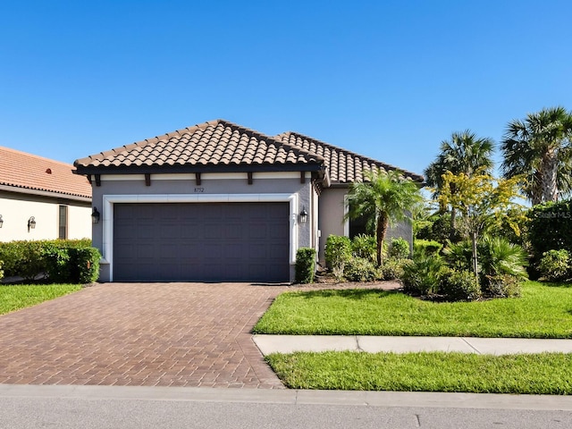 mediterranean / spanish-style home featuring a garage and a front lawn