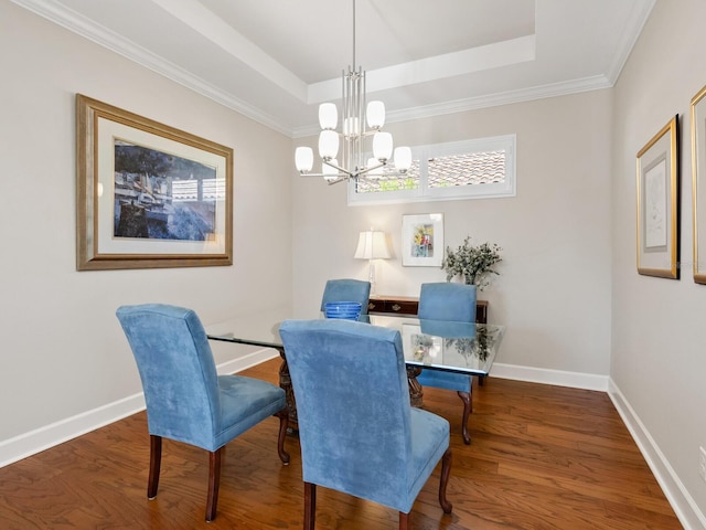 dining room featuring a raised ceiling, dark hardwood / wood-style flooring, ornamental molding, and a notable chandelier