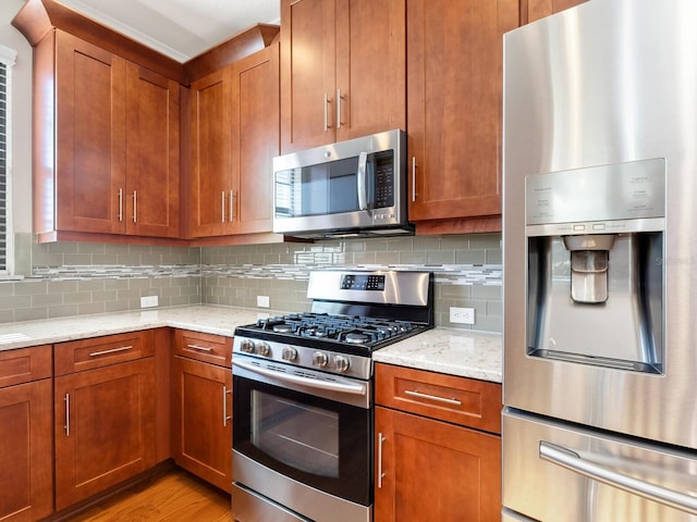 kitchen with light stone countertops, stainless steel appliances, light hardwood / wood-style flooring, and tasteful backsplash