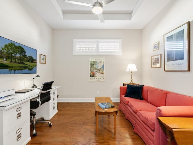 office area featuring hardwood / wood-style flooring, ceiling fan, and a tray ceiling