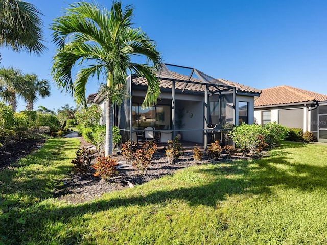 rear view of property featuring glass enclosure and a lawn