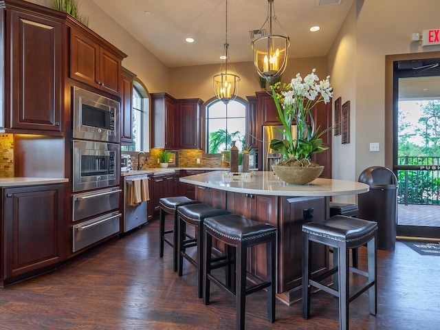 kitchen featuring pendant lighting, a breakfast bar, an inviting chandelier, a kitchen island, and stainless steel appliances