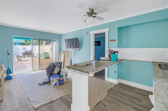 interior space with kitchen peninsula, tasteful backsplash, ornamental molding, ceiling fan, and light hardwood / wood-style floors