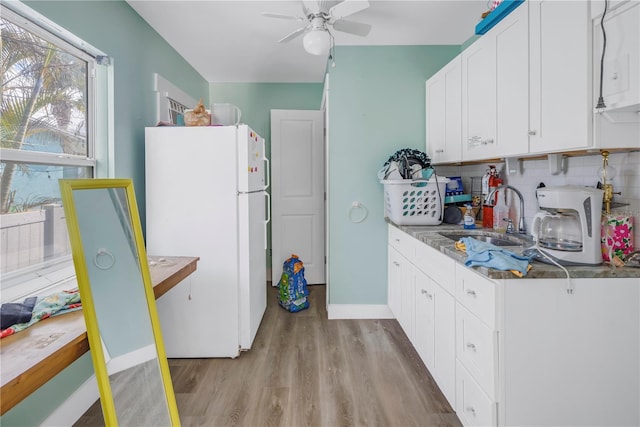 kitchen featuring light wood-type flooring, backsplash, sink, white fridge, and white cabinetry