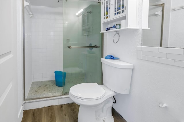 bathroom with hardwood / wood-style floors, toilet, and an enclosed shower