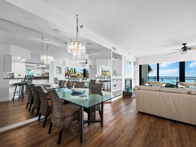 dining area with ceiling fan with notable chandelier, dark hardwood / wood-style floors, a water view, and built in shelves