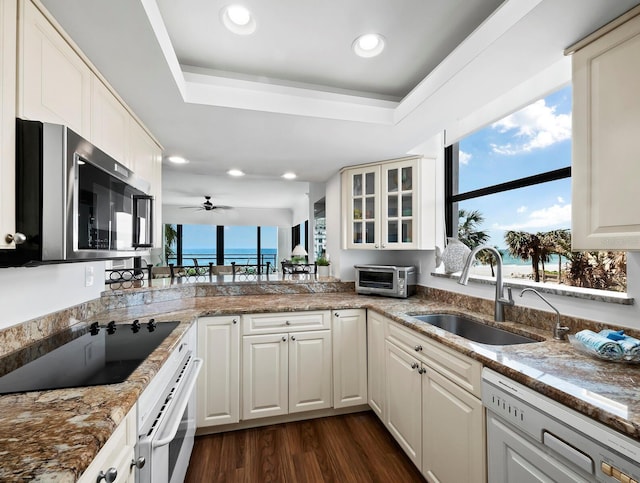 kitchen with white appliances, white cabinetry, a raised ceiling, and sink