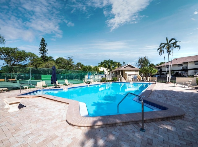 view of swimming pool with a patio and tennis court