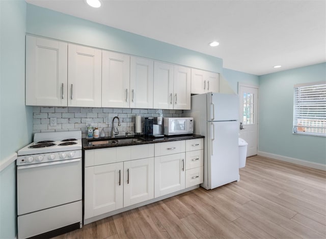 kitchen featuring white appliances, backsplash, white cabinets, sink, and light hardwood / wood-style flooring