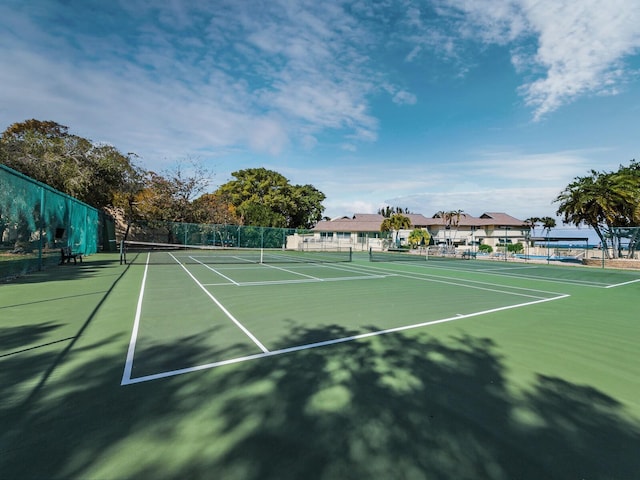 view of tennis court with community basketball court and fence